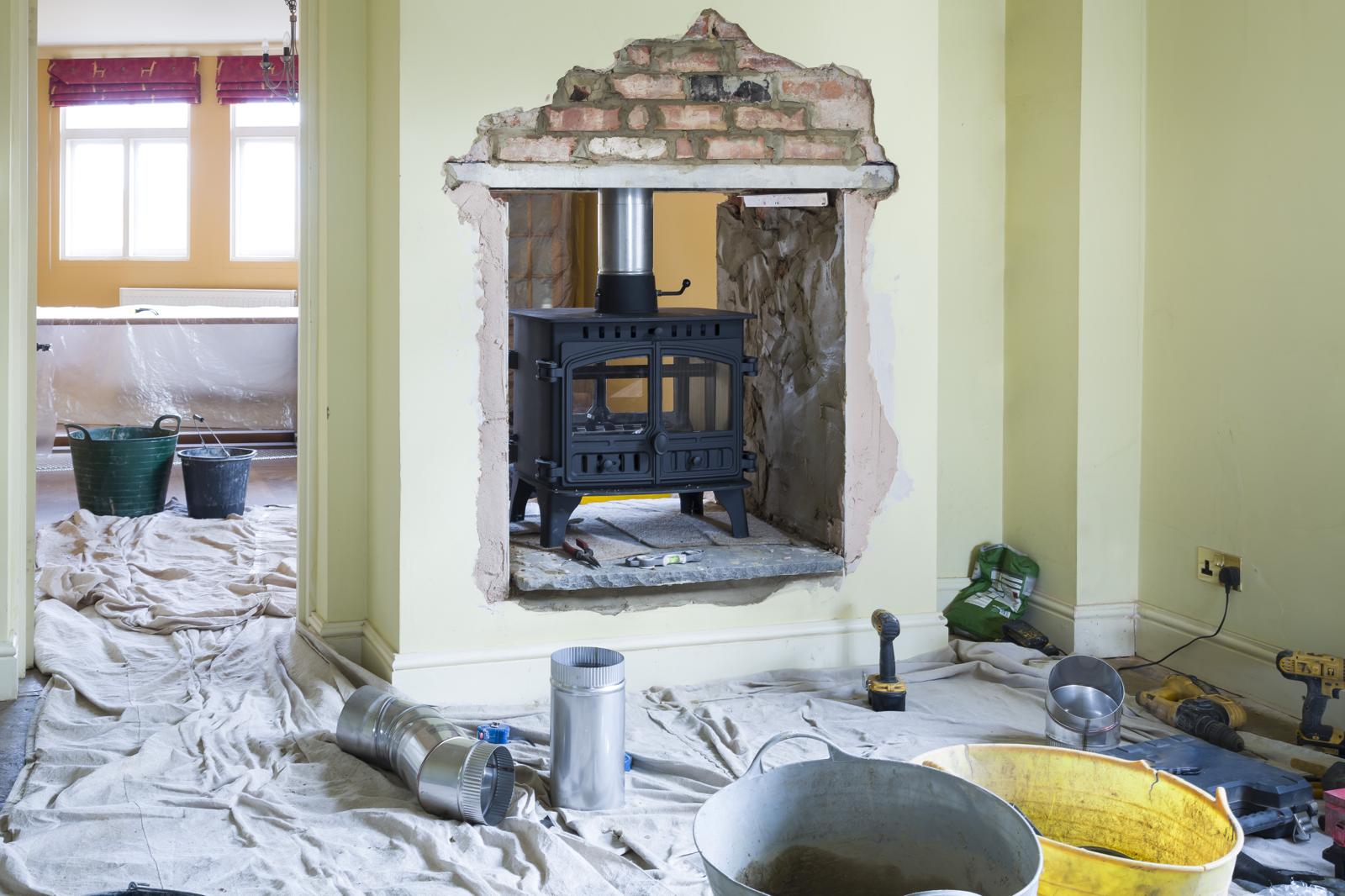 Wood-burning stove being installed into a brick fireplace opening